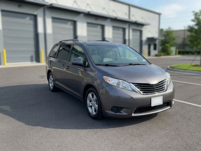 Example loaner car: a gray minivan parked outside an auto body shop