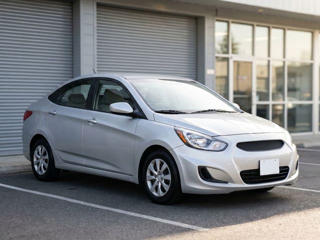 Example loaner car: a silver compact sedan parked outside an auto body shop